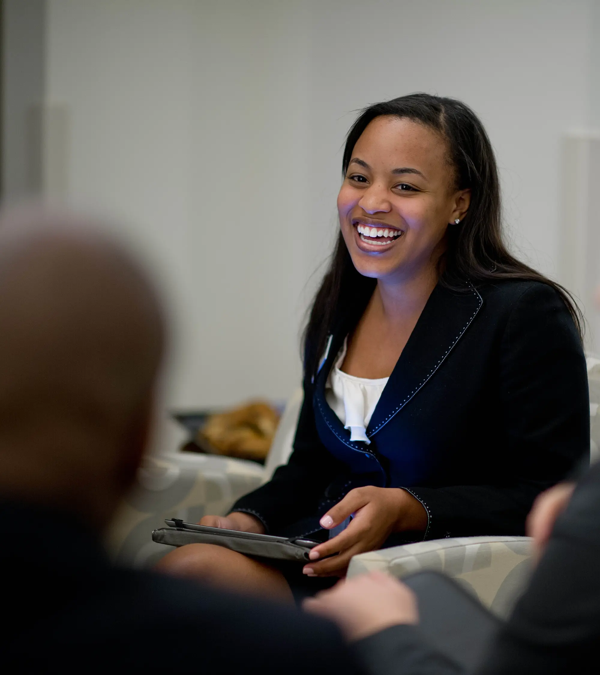 woman holding an iPad while smiling and talking to someone at work
